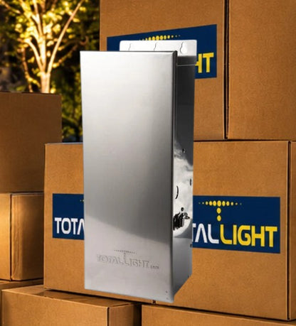 A tall, brushed-metal rectangular product stands in front of stacked brown cardboard boxes. The front box has a blue and yellow TotalLight logo sticker, and the product itself appears branded with 'ROYAL-LIGHT' near the bottom.