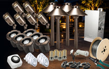 Load image into Gallery viewer, Outdoor landscape lighting kit with multiple bronze-toned spotlights, a four-light pole kit, a white electrical box, wire spools, mounting hardware, and wiring tools, arranged together on a dark background with warm lights in the distance.
